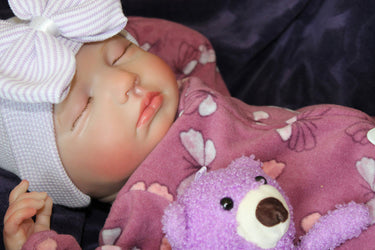 reborn doll sleeping in purple outfit